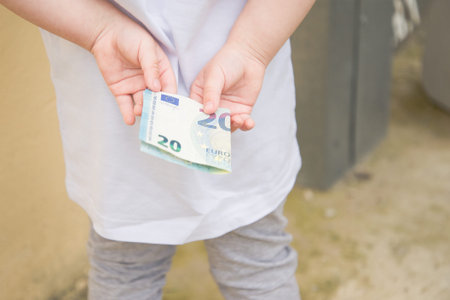 childs hands behind his back with a Euro bill