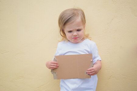 three-year-old girl holding a cardboard sheet mock-up sad faceの写真素材