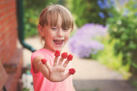 Happy little child with raspberry outdoorsの写真素材