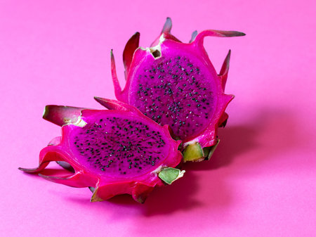 Pink pitahaya on a pink background. Close up. Tropical dragon fruit cut in half displaying vivid...
