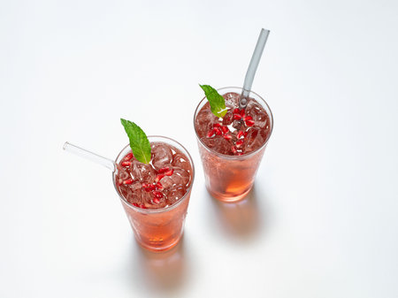 Pomegranate juice on a white background in a glass glasses with a glass straws.