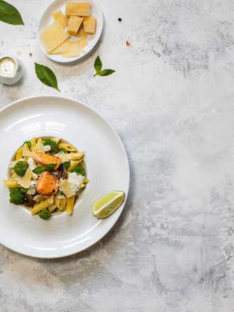 Pasta penne with salmon, broccoli and pesto sauce on white-gray background. Flat lay.