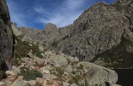 beautiful scenery of two high mountain lakes in corsician alpes with rocks green bushes and blue sky background on gr20 famous trekの写真素材