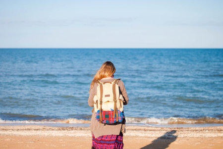 A girl stands back and looks at the sea. Hippie Girl looks at the sea. Woman with a bottle of wine...