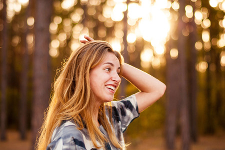 Young lone girl smiling at sunset in the forest.の写真素材