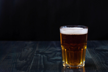 Just a glass of beer on a wooden table. A glass of light beer on a dark background. Light beer in a glass.の写真素材