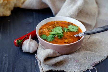 Georgian soup kharcho with cilantro and vegetables. The national Georgian dish is served with fresh lavash. Soup kharcho with vegetables and cilantro on a wooden table.の写真素材