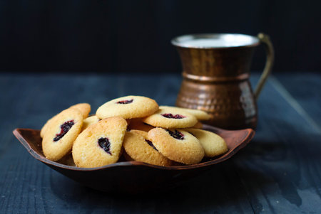 Shortbread cookies and milk in an oriental copper mug. Eastern cookies on a dark background and a...