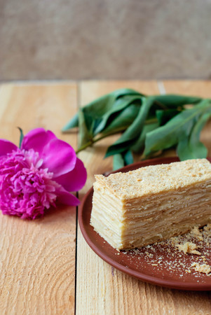 Cake Napoleon on a wooden table with a peony flower.の写真素材