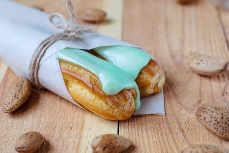 Almond eclairs in the glaze on a wooden table