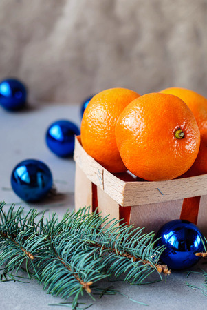 Mandarins in a wooden box with Christmas toys with spruce branches and a garlandの写真素材