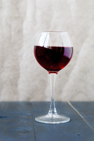 A glass of red wine on a wooden table on a light backgroundの写真素材