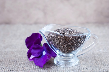 Chia seeds in glassware with purple flowers on a linen tablecloth in a rustic styleの写真素材