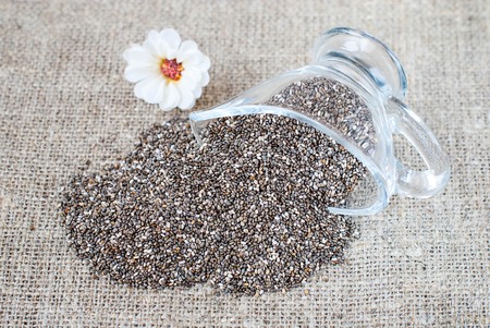 Spilled chia seeds on a linen tablecloth in a rustic style with utensilsの写真素材