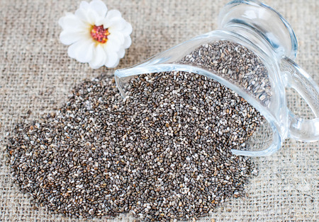 Spilled chia seeds on a linen tablecloth in a rustic style with utensilsの写真素材