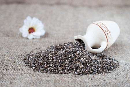 Spilled chia seeds on a linen tablecloth in a rustic style with utensilsの写真素材