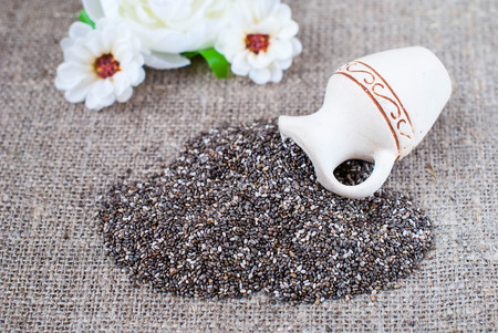 Spilled chia seeds on a linen tablecloth in a rustic style with utensilsの写真素材