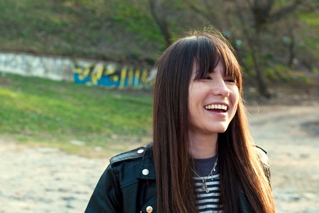 beautiful girl with a bang and long hair laughs in a vest and a leather jacketの写真素材