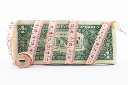 Measuring tape over money, budgeting, measure money, tight budget. Rolled tape shown.の写真素材