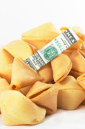 Chinese Fortune Cookie on a heap with money, cash neatly folded inside the snack, on white background, many behind, to show one out of many.の写真素材