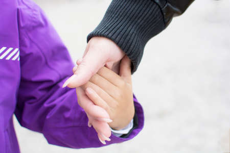 Close up hand of mother holding and lead her child in winter season, family conceptの写真素材
