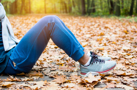 Attractive Asain male relaxing before fitness in the autumn park, man sitting on beautiful leaves...