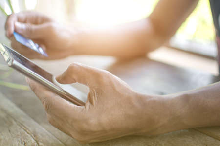 Close up hand of man holding the blank screen of moblie phone and credit card to pay the product shopping onlineの写真素材