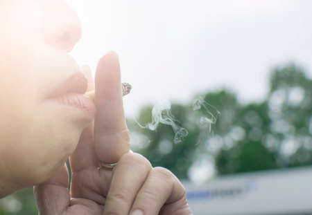 Asian old woman smoking a cigarette with bokehの写真素材