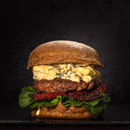 <p>An artisan hamburger with roquefort cheese and sundried tomatoes plus arugula on a black background</p>の写真素材