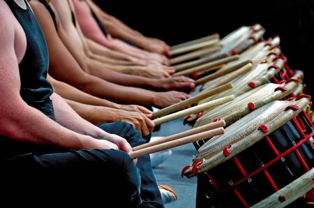 A picture from the neck down of a group of drummers with sticks in hand seating in front of  their drums. の写真素材