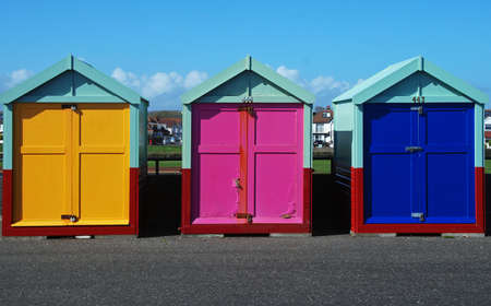 A row of three British beach huts with brighly painted doorsのeditorial素材