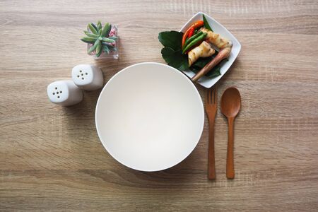 Empty bowl for text input or food and have spoon, forks and have side dishes are placed on a brown wooden table.の写真素材