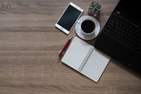 Note books, pens, coffee, mobile phones and laptop are placed on table wooden and have space for text input. copy spaceの写真素材
