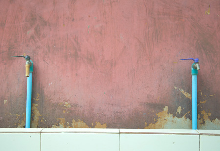 Old faucet on concrete red wall backgroundの写真素材