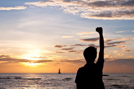 Successful man raising arms on the beach sunsetの写真素材