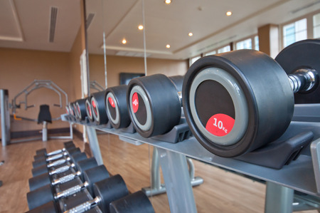 Different sizes and weights dumbbells on stand in modern gymのeditorial素材