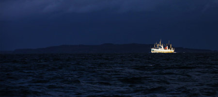 Bright cargo ship and very dark sea