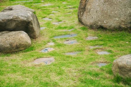 Stone walkway with green grass (lawn) and big rock in the gardenの写真素材