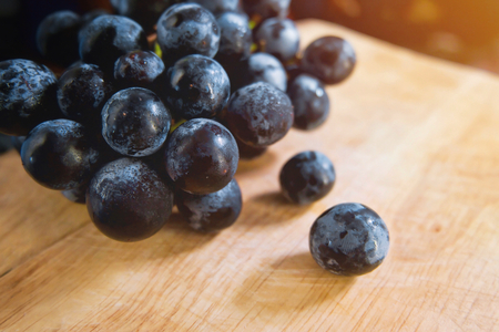 Black grape in wooden tray with sunlight. Fruit background.の写真素材