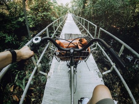 Man is cycling with Vintage camera bag on basket in the natural path with sunlight at Bang Krachao (the Green Lung of Bangkok), Samut prakan, Thailandの写真素材