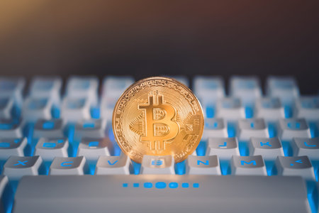 Gold bitcoin on a white keyboard with blue light or RGB keyboard. Cryptocurrency virtual money....