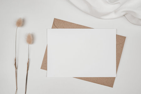 Blank white paper on brown paper envelope with Rabbit tail dry flower and white cloth. Mock-up of...