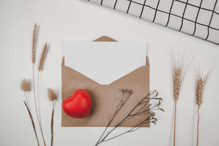 Blank white paper is placed on open brown paper envelope with red heart, Many kinds of dried flowers, White cloth on Black background. Valentine's day concept #valentine #card #gift #template #mockupの写真素材