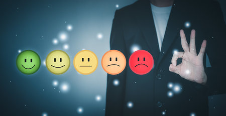 Customer service evaluation and satisfaction. Smile rating to feedback survey concept. Man wearing black suit and Hand making ok sign.の写真素材