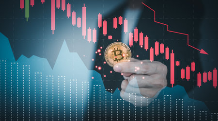 Bitcoin price crash falling down with graph. Man hand holding cryptocurrency. Bear market concept.の写真素材