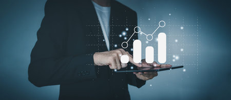 Success business concept. Businessman hand holding tablet with hologram of statistics graph and char...