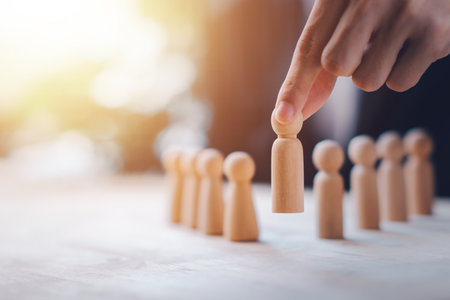 HR manager (human resources) or Employer hand choose takes person wooden doll. Leader stands out from crowd. Looking for good worker. HR, HRM, HRD concepts.の写真素材