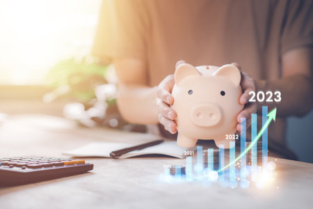 Piggy bank with man calculating income and return on investment in 2023. Saving money wealth and financial increased. Business, finance, investment, Financial planning, Trend, Tax, Return.の写真素材