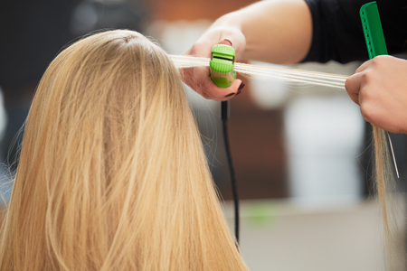 Hairdresser straighten hair with straightenerの写真素材