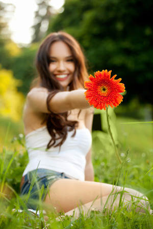 Beautiful Woman With Gerbera Flower Enjoying Nature against Nature Backgroundの写真素材